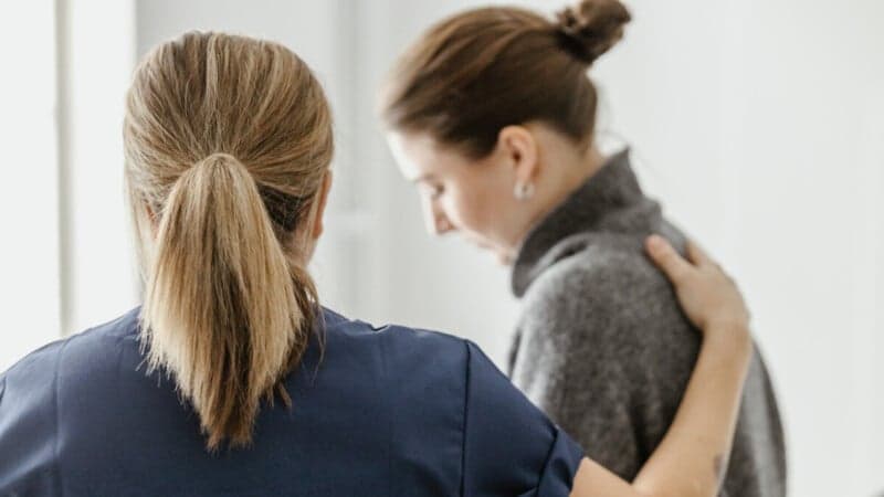 Kvinna håller handen på annan kvinnas rygg