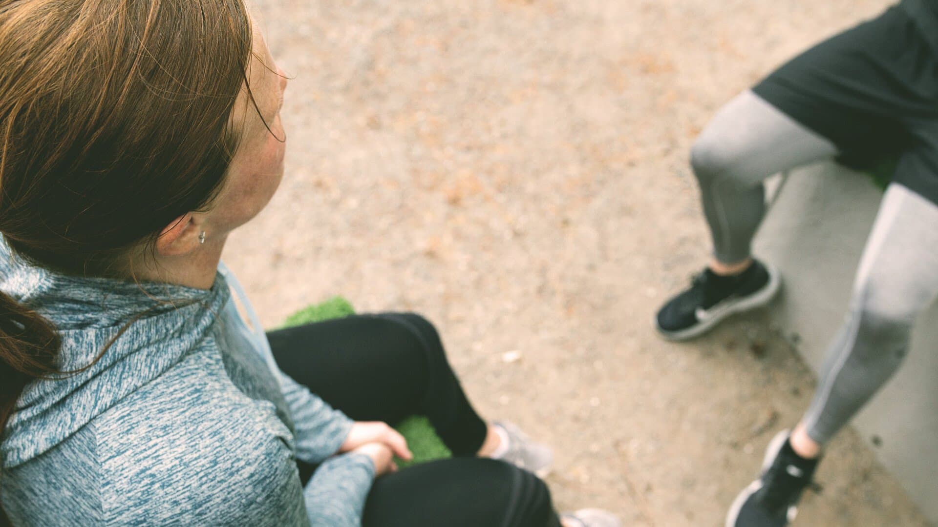 Kvinna i träningskläder sitter utomhus