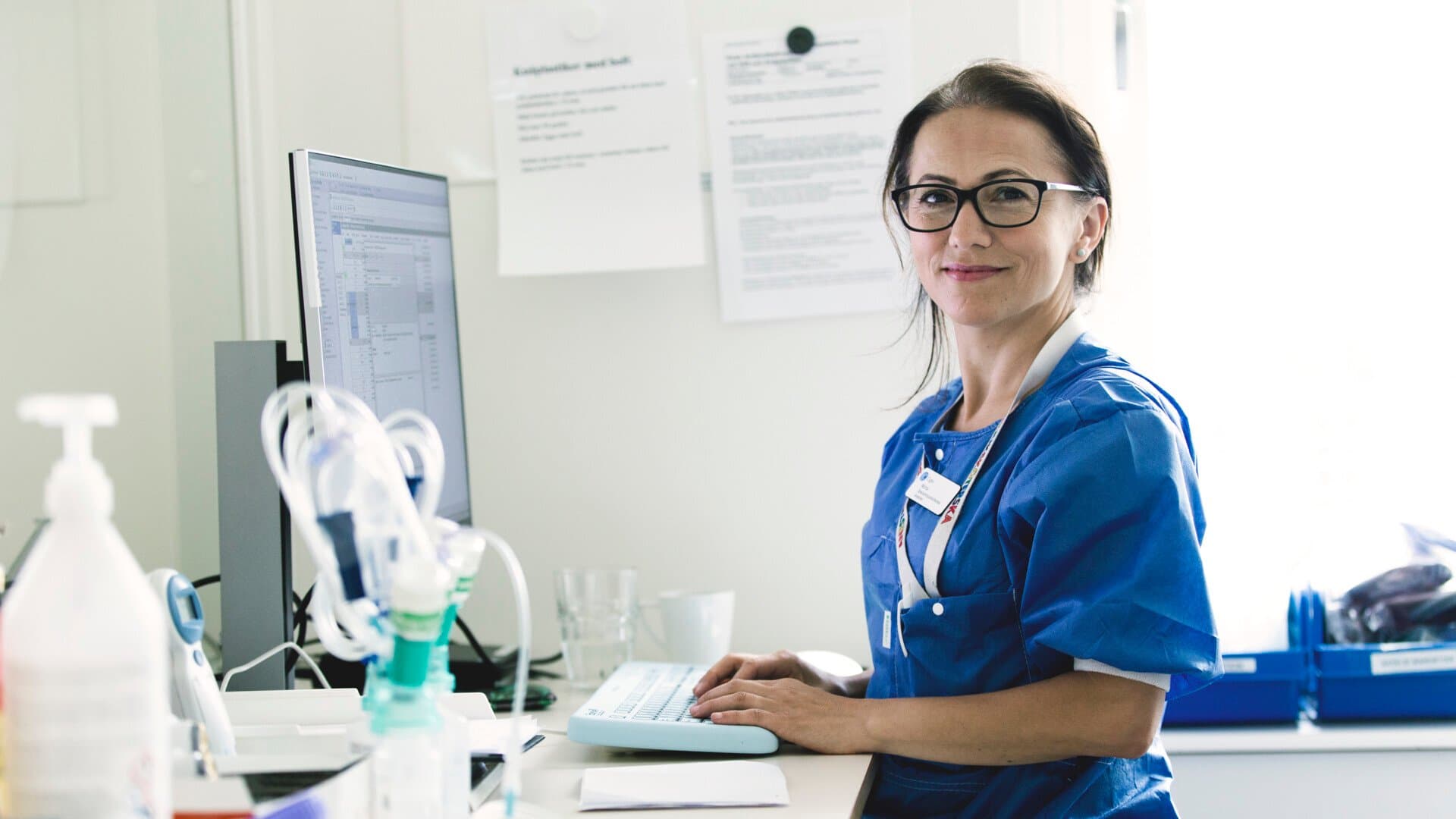 Sjukvårdsklädd kvinna vid arbetsstation
