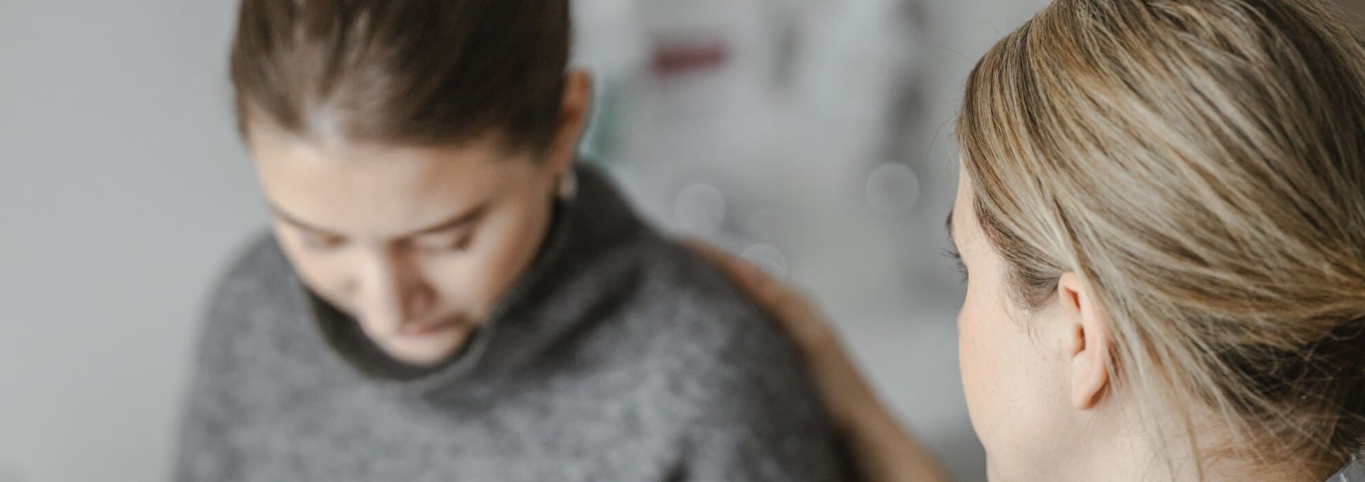 Kvinna håller hand på annan kvinnas rygg