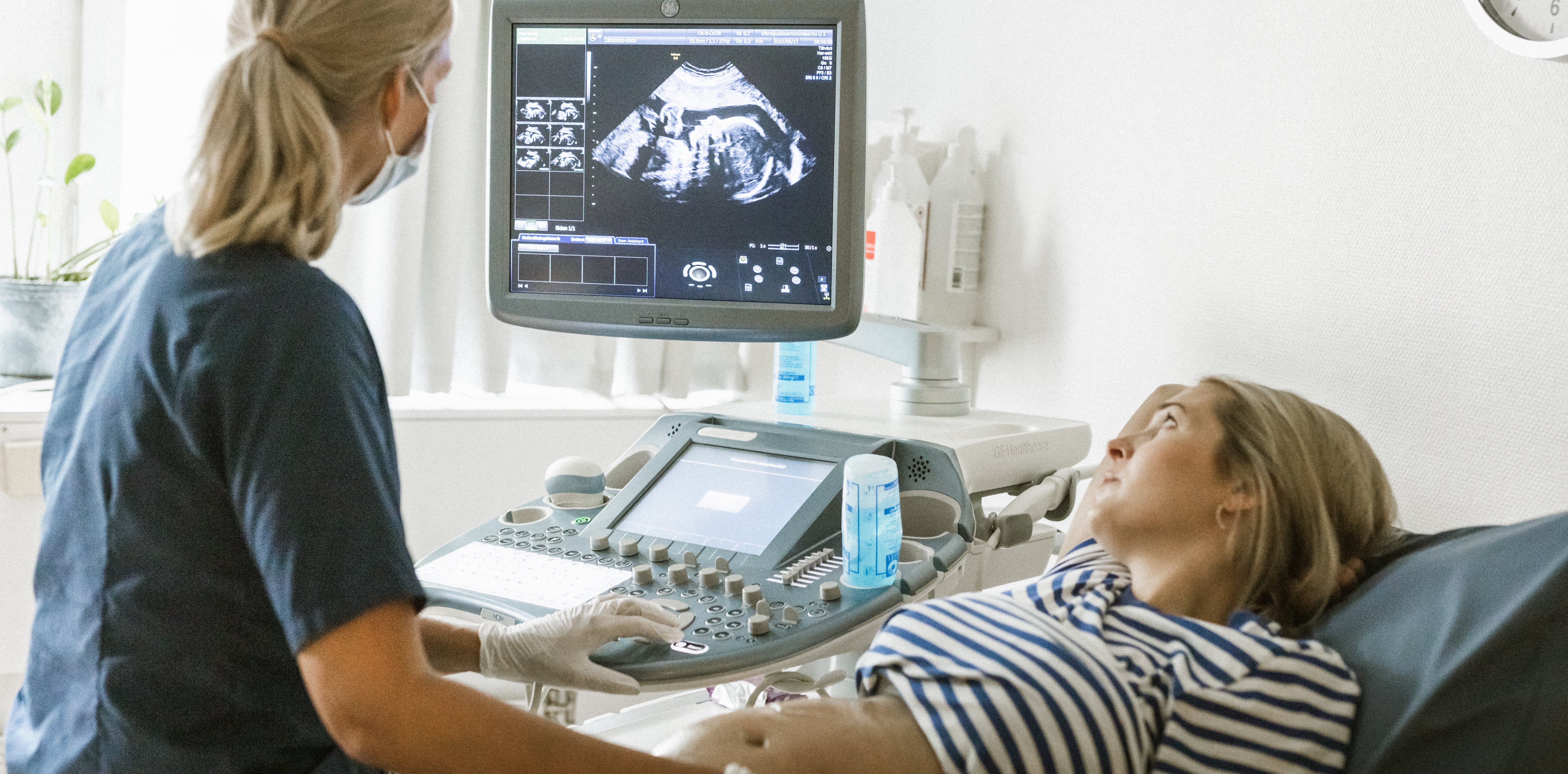 Sjukvårdklädd personal utför ultraljud på patient Sjukvårdklädd personal utför ultraljud på patient