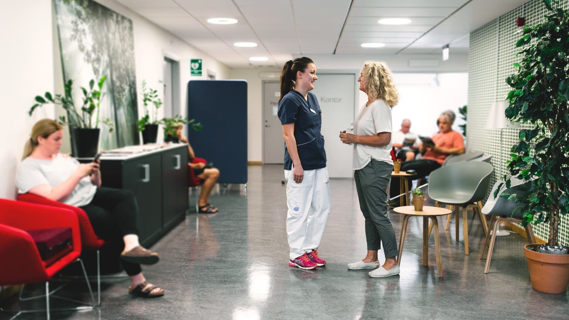 Vårdpersonal pratar med patient i väntrummet